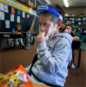 Kindergartner Michael  Engle, 5, of Levittown, keeps his face shield on while munching on cheese curls during snack time at St. Michael the Archangel School in Levittown, on Friday, Jan. 29, 2021.