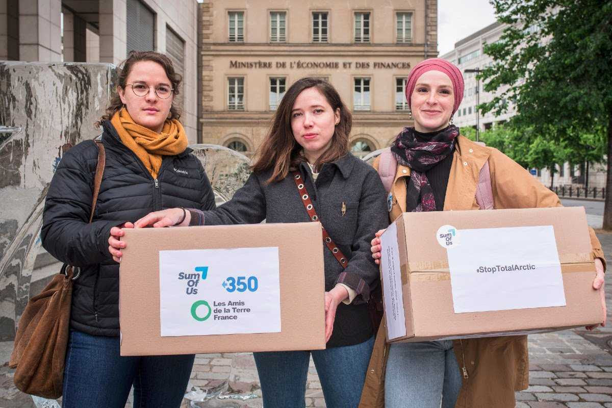Photos of the three campaigners in front of the Ministry carrying the boxes containing the 200,000 signatures