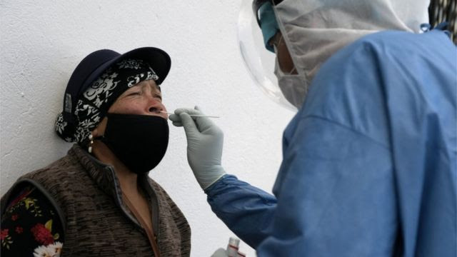 Profissional de saúde coleta amostra do nariz de uma mulher equatoriana para exame de covid-19