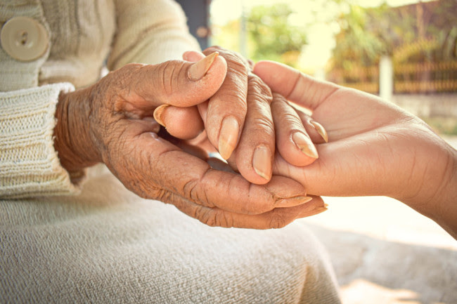 Young and Old Woman Holding Hands - Shutterstock