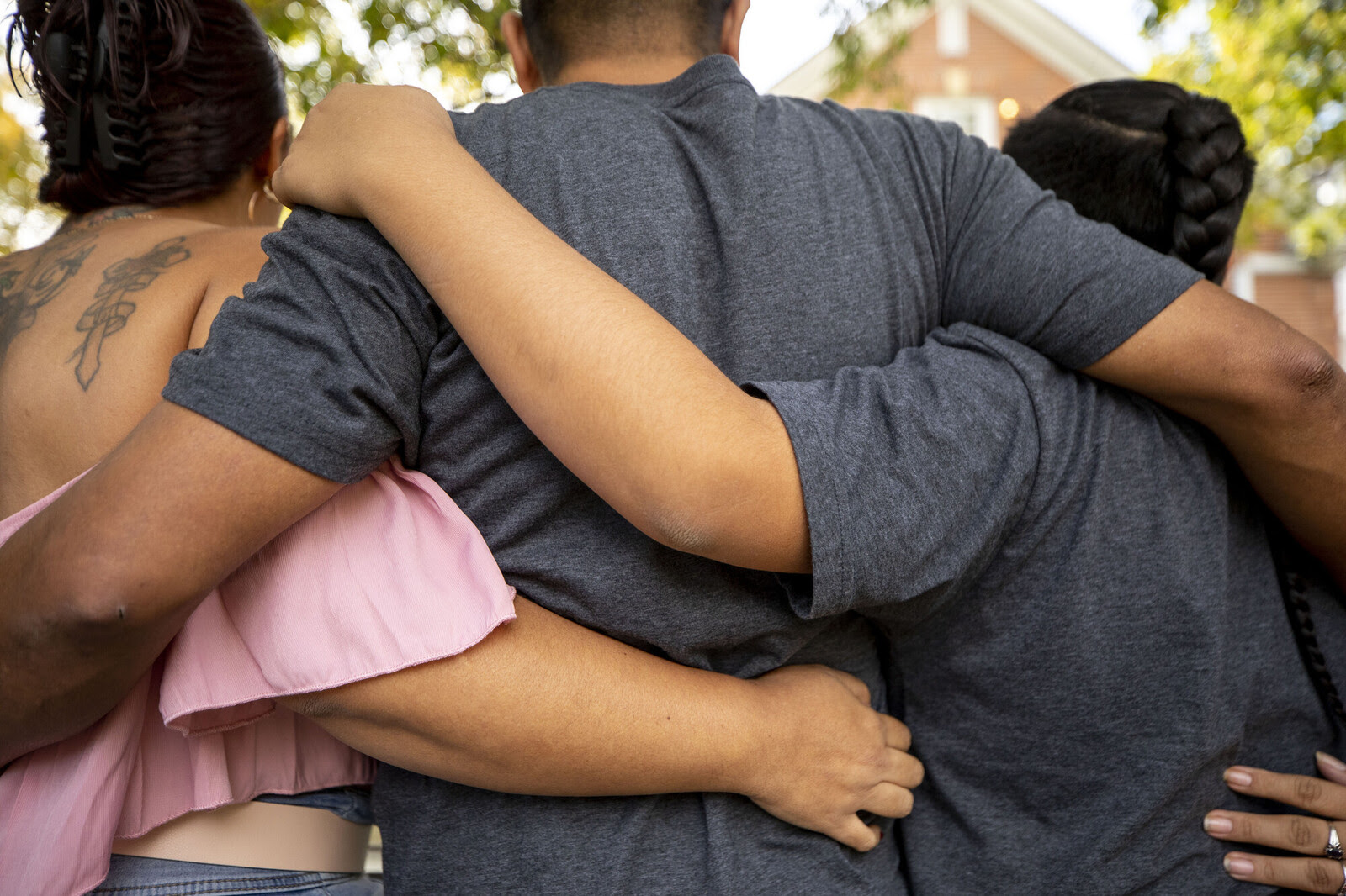photo of a family seen from behind, standing close together with arms wrapped around one another