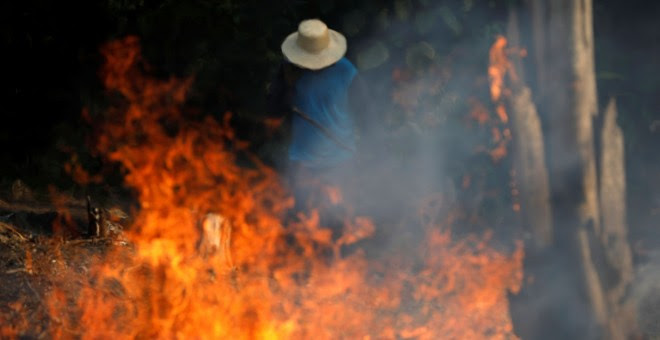 Un hombre trabaja en un tramo de la Amazonia en llamas. / Reuters