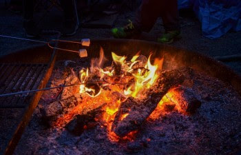 Red-hot coals cast glowing red, orange and yellow light into the purple light of late evening.