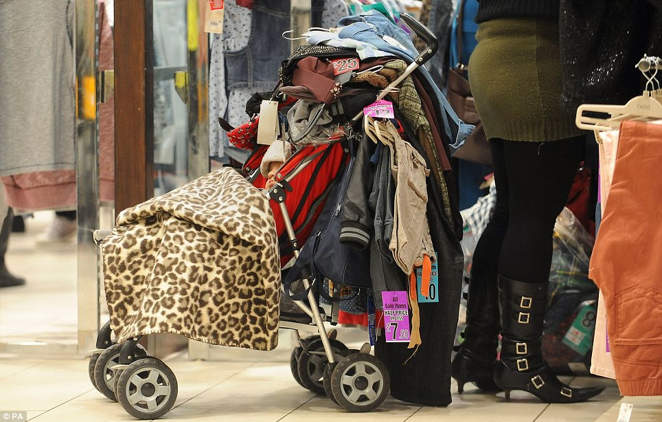 Engulfed: A baby in a pushchair which his mother has covered in clothes at the Highcross shopping centre in Leicester