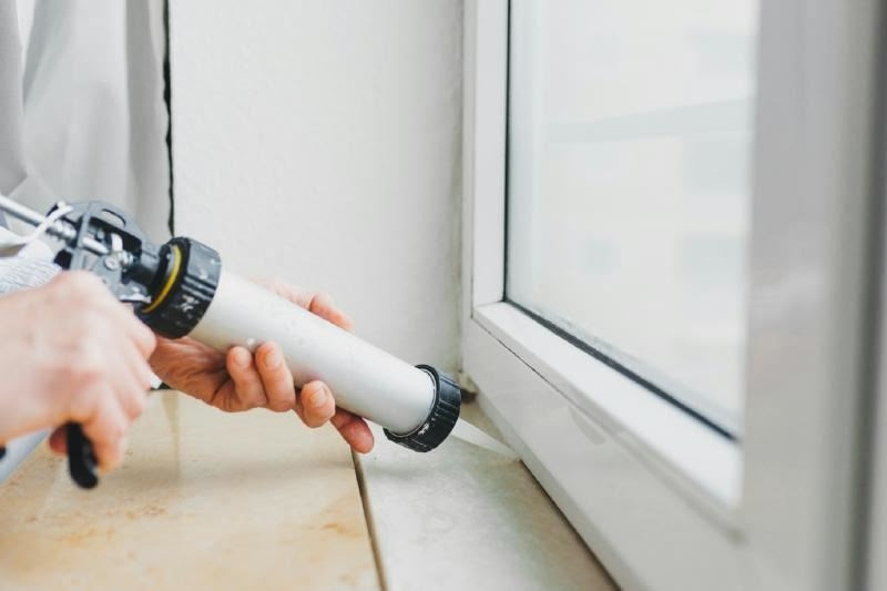 A person using a silicone sealant to seal a window Description automatically generated