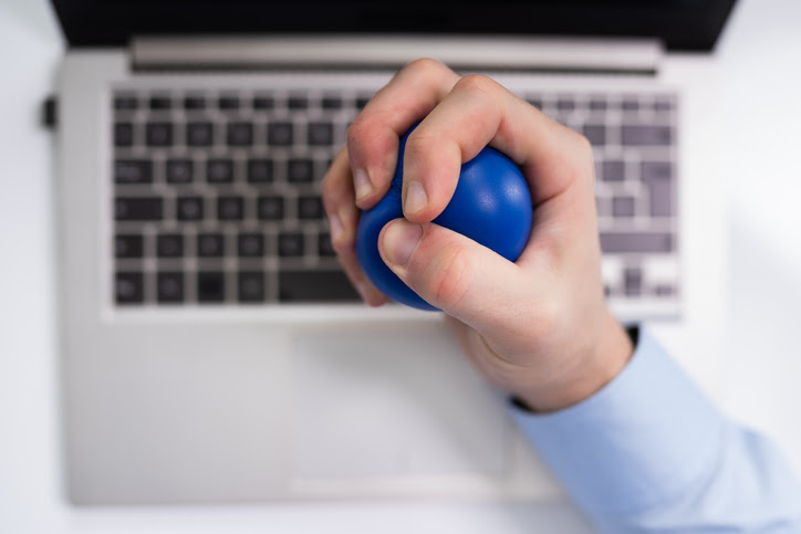 hand squeezing a stress ball over a computer
