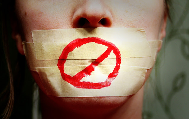 A young woman with tape over her mouth and the ''anti'' sign in red market or paint