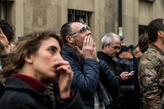 Slide 14 of 31: People watch the landmark Notre-Dame Cathedral burning in central Paris on April 15, 2019- A fire broke out at the landmark Notre-Dame Cathedral in central Paris, potentially involving renovation works being carried out at the site, the fire service said. (Photo by Nicolas Liponne/NurPhoto via Getty Images)