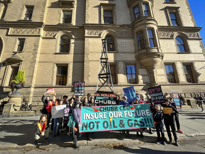 Protestors with a two-story derrick in front of Chubb's CEO's home.