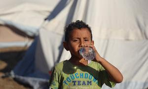 Un niño de cinco años bebe agua embotellada entregada por UNICEF en el campamento de Jan Yunis.