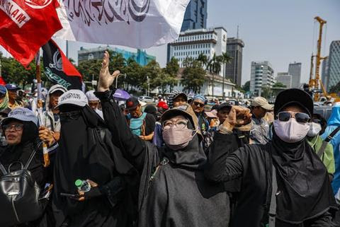 Masked people in a large protest.