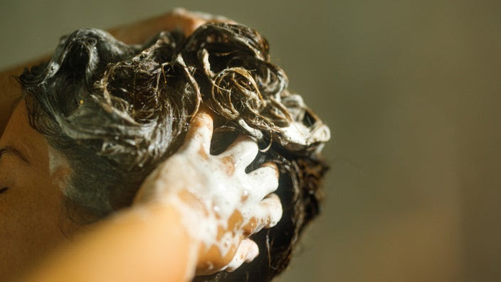 A close-up of someone shampooing their hair.