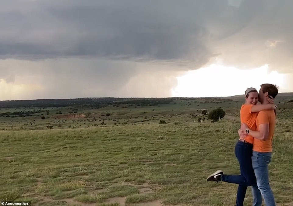 A couple embracing in front of a large tornado after they just got engaged A couple embracing in front of a large tornado after they just got engaged