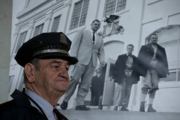 SAN FRANCISCO, CA - MARCH 21:  Former Alcatraz Island prison guard Jim Albright stands next to a photograph of himself that is part of an exhibit of photographs documenting the last day of Alcatraz federal penitentiary on March 21, 2013 in San Francisco, California.  The National Park Service marked the 50th anniversary of the closure of the notorius Alcatraz federal penitentiary with an exhibit of newly discovered photos by Los Angeles freelance photographer Leigh Wiener of the prison