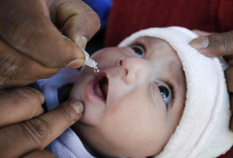 A child is given an oral Polio vaccination by a NGO worker in Indian Kashmir