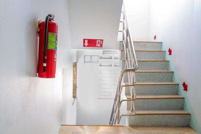 A fire extinguisher and exit sign in a stairwell.