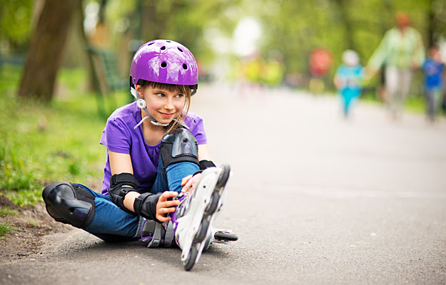 A young girl in rollerblades and protective gear.