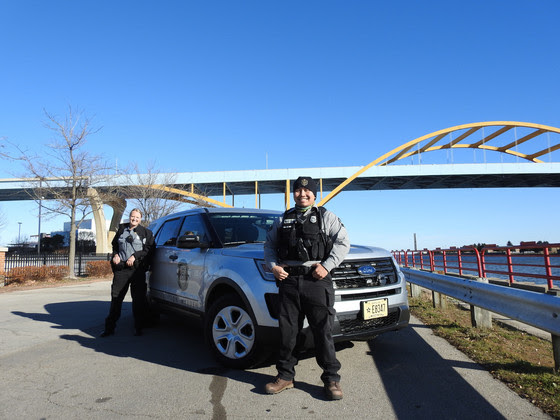 A male and female warden standing in front of their SUV near the Hoan Bridge in Milwaukee.