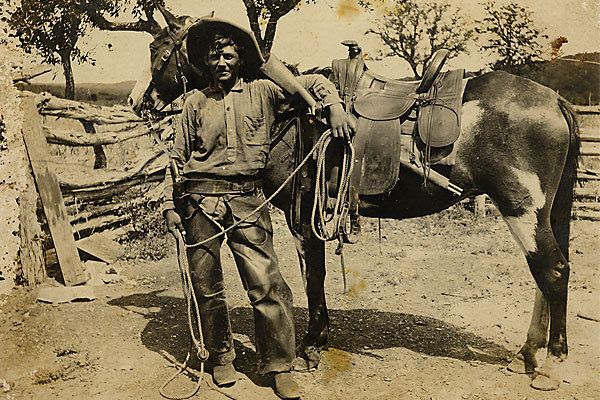 Judging by the saddle style, this unidentified cowboy was working in the late 1870s or 1880s. In his holster, he carries a Colt model 1873 single action revolver with hard rubber grips, and he has looped his left arm around a Winchester model 1873 carbine in a saddle scabbard. On the back is the light pencil inscription Indian fighter. :