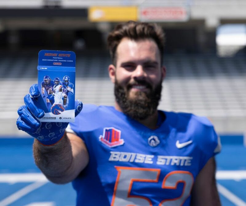Boise State football player is holding a pack of football trading cards