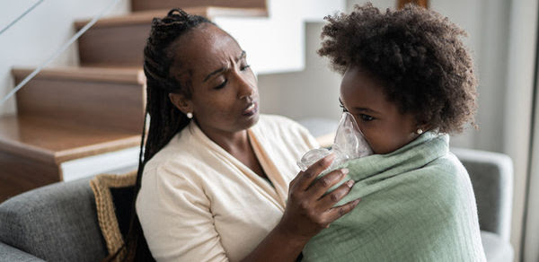 A black mother adjusting her child's oxygen mask.