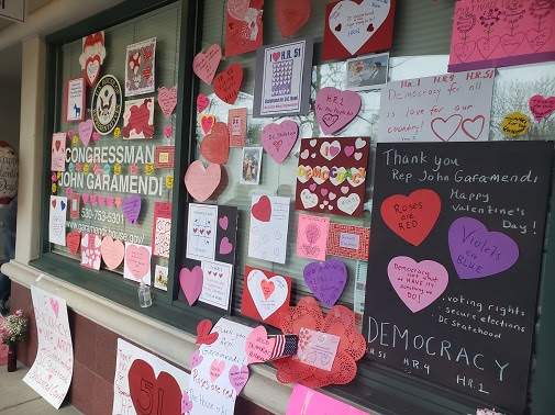 Congressman John Garamendi's Davis office window, covered with handmade valentine's day hearts and posters advocating for HR1, HR4, HR51, voting rights, secure elections, DC statehood