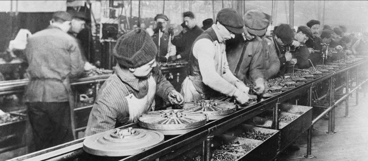 A black-and-white photo of men working on a Ford assembly line.