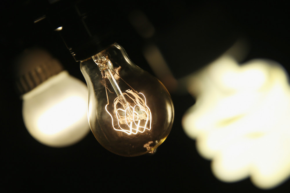 A vintage-style incandescent light bulb is shown with an LED light bulb and a compact florescent light bulb.