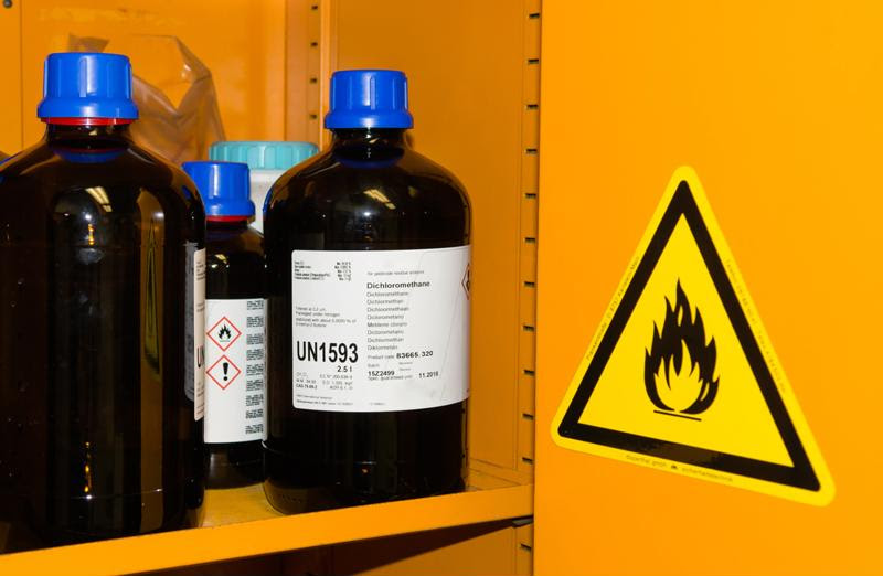 A cabinet of chemicals with warning labels.