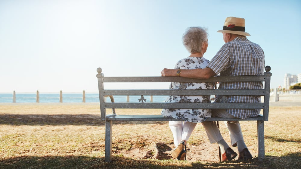 Senior couple sitting on a bench on the beach
