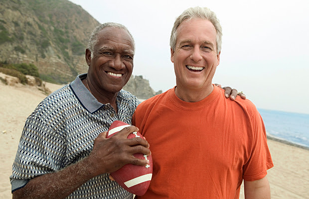 Two men on the beach holding a football.
