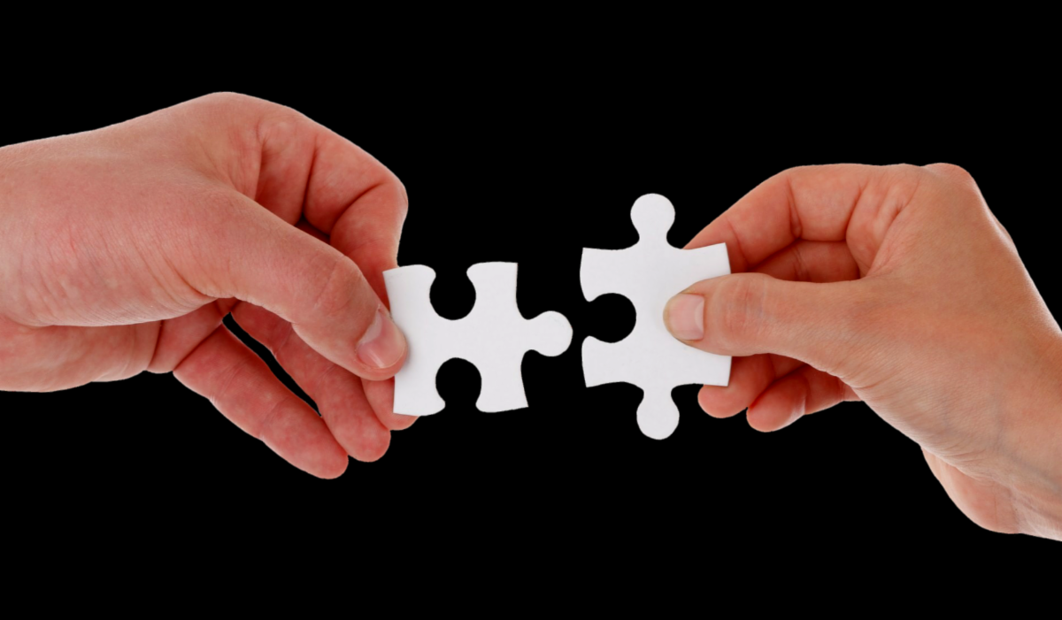 Two hands connecting two separate puzzle pieces. 