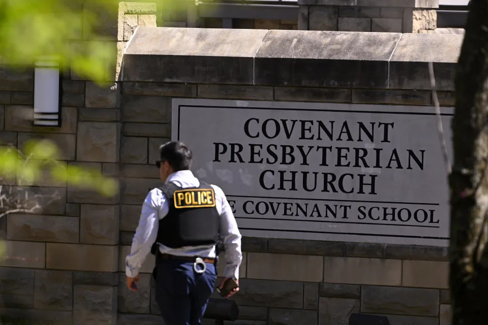 A police officer walks by an entrance to The Covenant School after a shooting in Nashville, Tenn. on Monday, March 27, 2023. (AP Photo/John Amis)