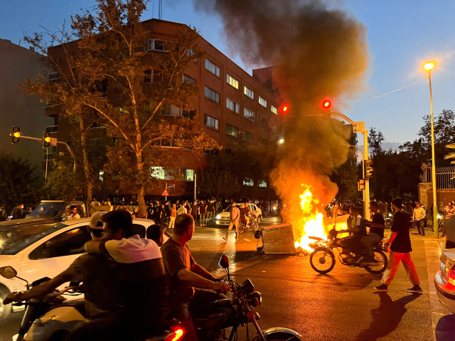 A police motorcycle burns during a protest over the death of Mahsa Amini, a woman who died after being arrested by the Islamic republic's "morality police", in Tehran, Iran September 19, 2022. WANA (West Asia News Agency) via REUTERS