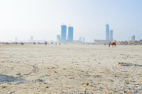 A vast white beach with skyscrapers in the distance.