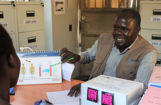 An antiretroviral treatment provider explains the importance of testing HIV viral load to Christine before her sample is collected.