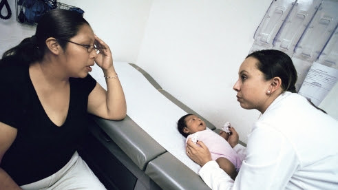  A doctor examines a baby while the mother watches.