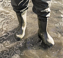 Person with heavy boots standing in floodwaters