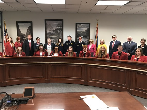 The Governor and the State Superintendent are surrounded by high school students who serve as state officers for Career Technical Student Organizations and their state advisors in a legislative committee meeting room.